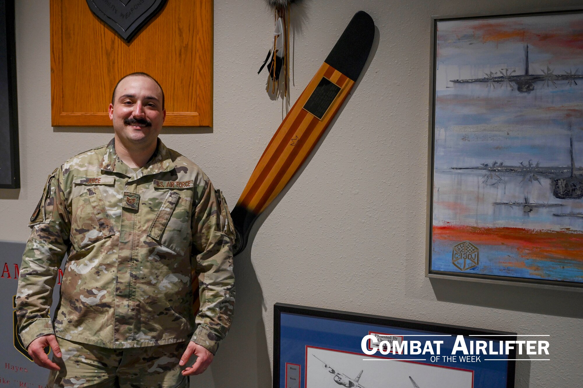 A man in uniform poses for a photo in front of a propeller.