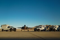An F-35A Lighting II and Multi-Utilization Secure Tactical And Network Ground Stations (MUSTANGS) are pictured on the flight line at Nellis Air Force Base, Nevada, Nov. 16, 2022. Part of the Crowd-Sourced Flight Data (CSFD) program, MUSTANGS is a mobile vehicle that can download, process, and offload important data from Quick Reaction Instrumentation Package (QRIP) equipped aircraft without the need for fixed operational test infrastructure. (U.S. Air Force Photo by Airman 1st Class Trevor Bell)
