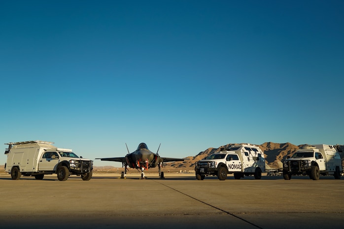 An F-35A Lighting II and Multi-Utilization Secure Tactical And Network Ground Stations (MUSTANGS) are pictured on the flight line at Nellis Air Force Base, Nevada, Nov. 16, 2022. Part of the Crowd-Sourced Flight Data (CSFD) program, MUSTANGS is a mobile vehicle that can download, process, and offload important data from Quick Reaction Instrumentation Package (QRIP) equipped aircraft without the need for fixed operational test infrastructure. (U.S. Air Force Photo by Airman 1st Class Trevor Bell)