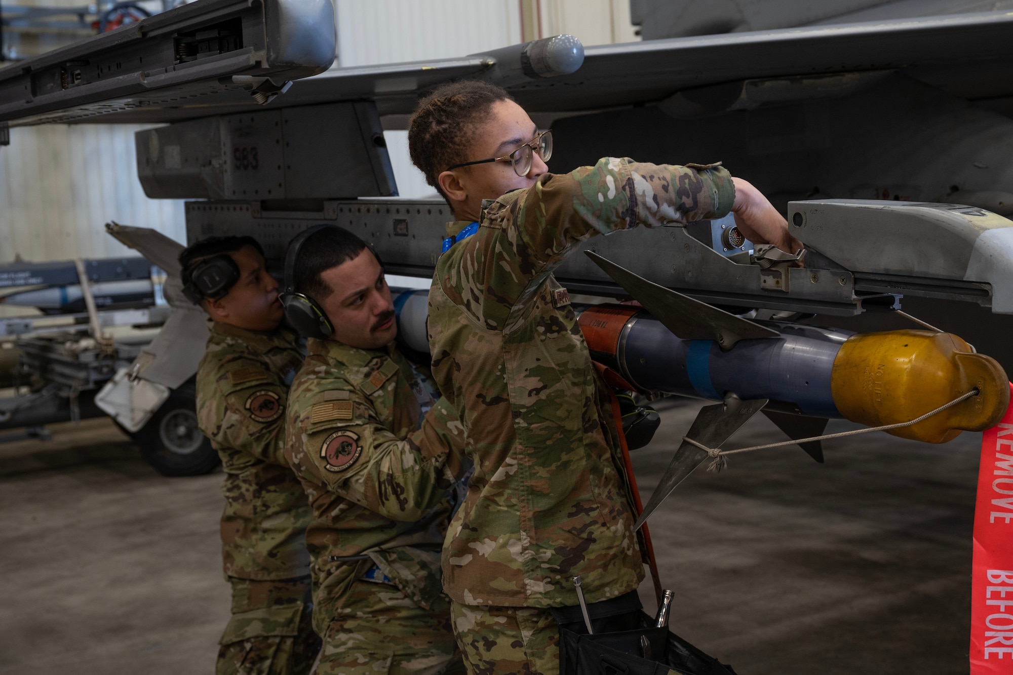 Load crew members from the 35th Fighter Generation Squadron hoist an Air Intercept Missile-9M to a F-16 Fighting Falcon.