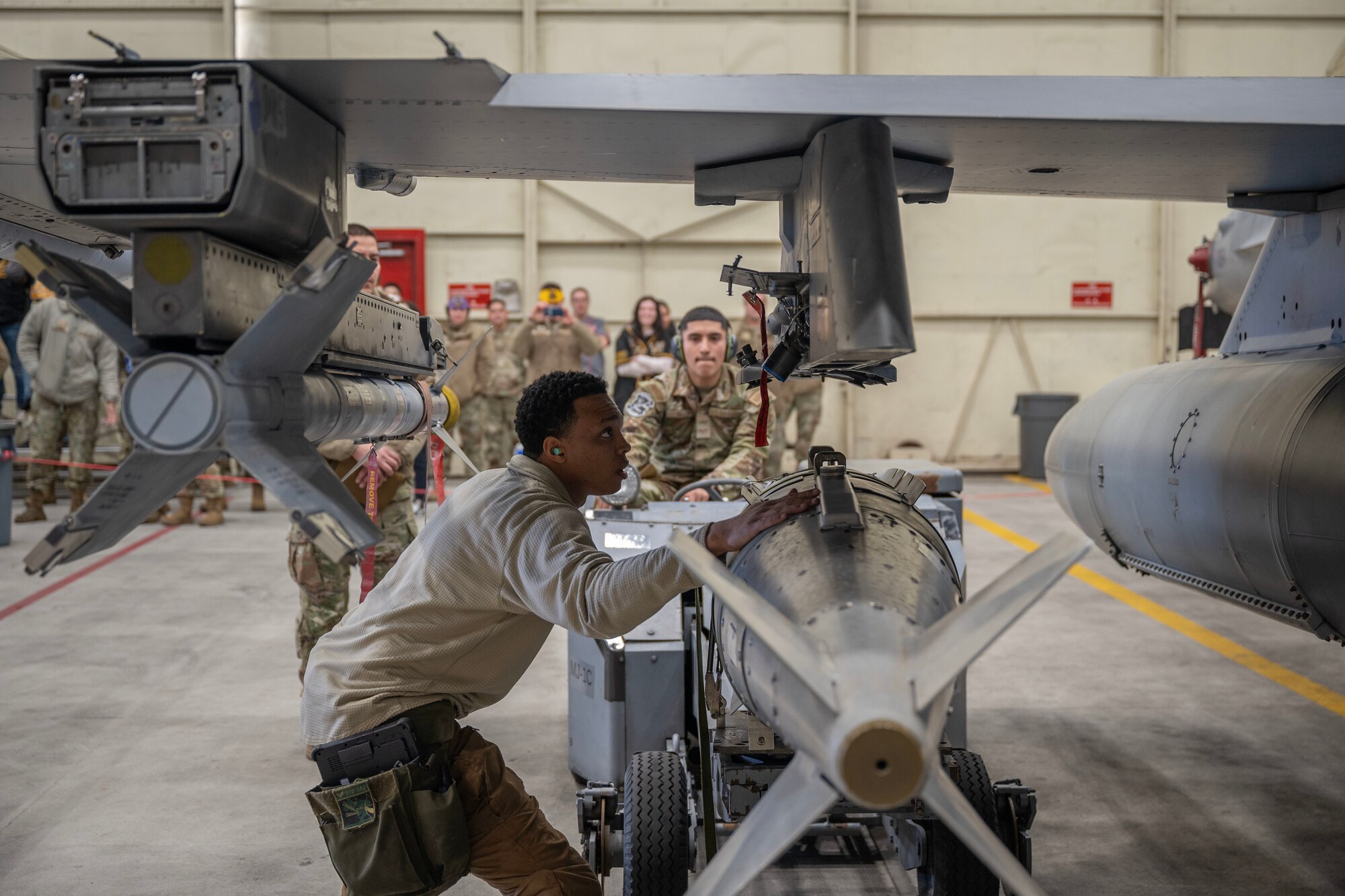 An Airman guides another Airman on installing and securing a guided bomb unit.