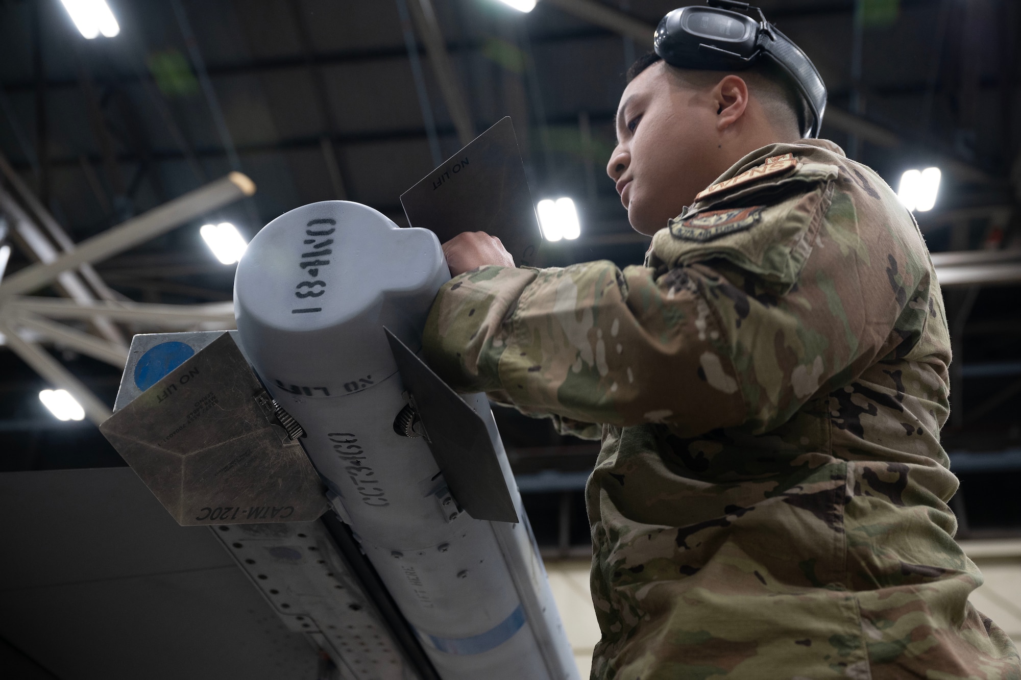 An Airman installs a metal fin on to a air intercept missile.