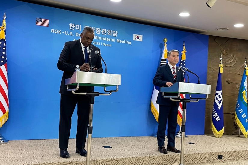 Secretary of Defense Lloyd J. Austin III  and South Korean counterpart stand behind lecterns on a podium with flags at either end and a blue backdrop.