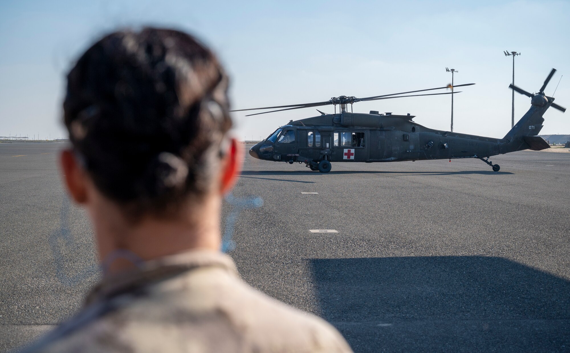 A Canadian Army medic watches as a U.S. Army UH-60 Blackhawk helicopter lands nearby at Ali Al Salem Air Base, Kuwait, Jan. 20, 2023.