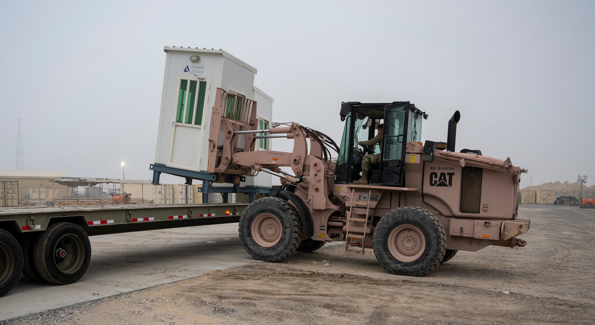 U.S. Air Force Airman 1st Class Felix Bojorquez, 386th Expeditionary Civil Engineer Squadron pavements and heavy equipment apprentice, loads a security cabin onto a trailer at Ali Al Salem Air Base, Kuwait, Jan. 25, 2023.