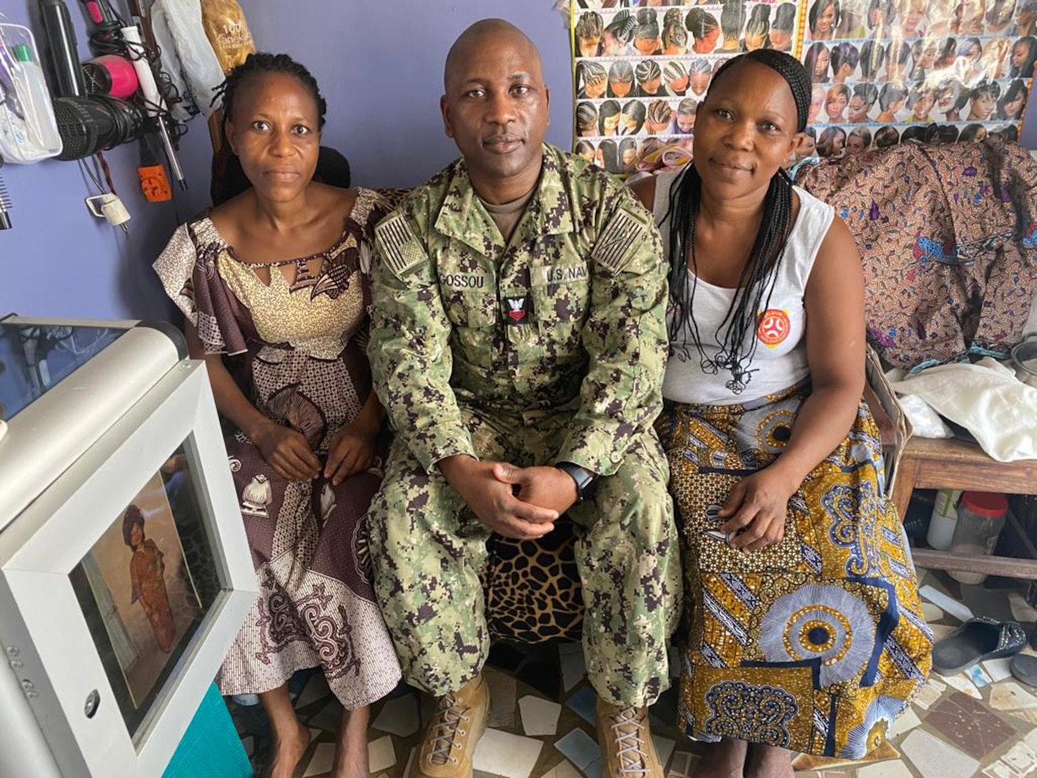 230130-N-NO901-1003 (Jan. 30, 2023) LAGOS, Nigeria - Hospital Corpsman 1st Class Agossou Marcellin, center, a Benin native, Pharmaceutical doctorate student, and U.S. Navy Reservist, poses for a photo with his sisters Alice Marcellin, left, and Marie in Marie’s beauty shop in Benin during exercise Obangame Express 2023. Obangame Express 2023, conducted by U.S. Naval Forces Africa, is a maritime exercise designed to improve cooperation, and increase maritime safety and security among participating nations in the Gulf of Guinea and Southern Atlantic Ocean. U.S. Sixth Fleet, headquartered in Naples, Italy, conducts the full spectrum of joint and naval operations, often in concert with allied and interagency partners, in order to advance U.S. national interests and security and stability in Europe and Africa. (Courtesy Photo)