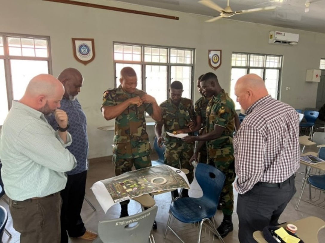 American instructors Mike Gerhard from the U.S. Army Corps of Engineers, Europe District; Alonzo Ellis from the U.S. Army Corps of Engineers, Fort Worth District and Dan Hunt from the U.S. Army Engineer School discuss proposed base camp design plans with engineers from the Ghana Armed Forces October 18, 2022, as part of a base camp design training course in Accra, Ghana.