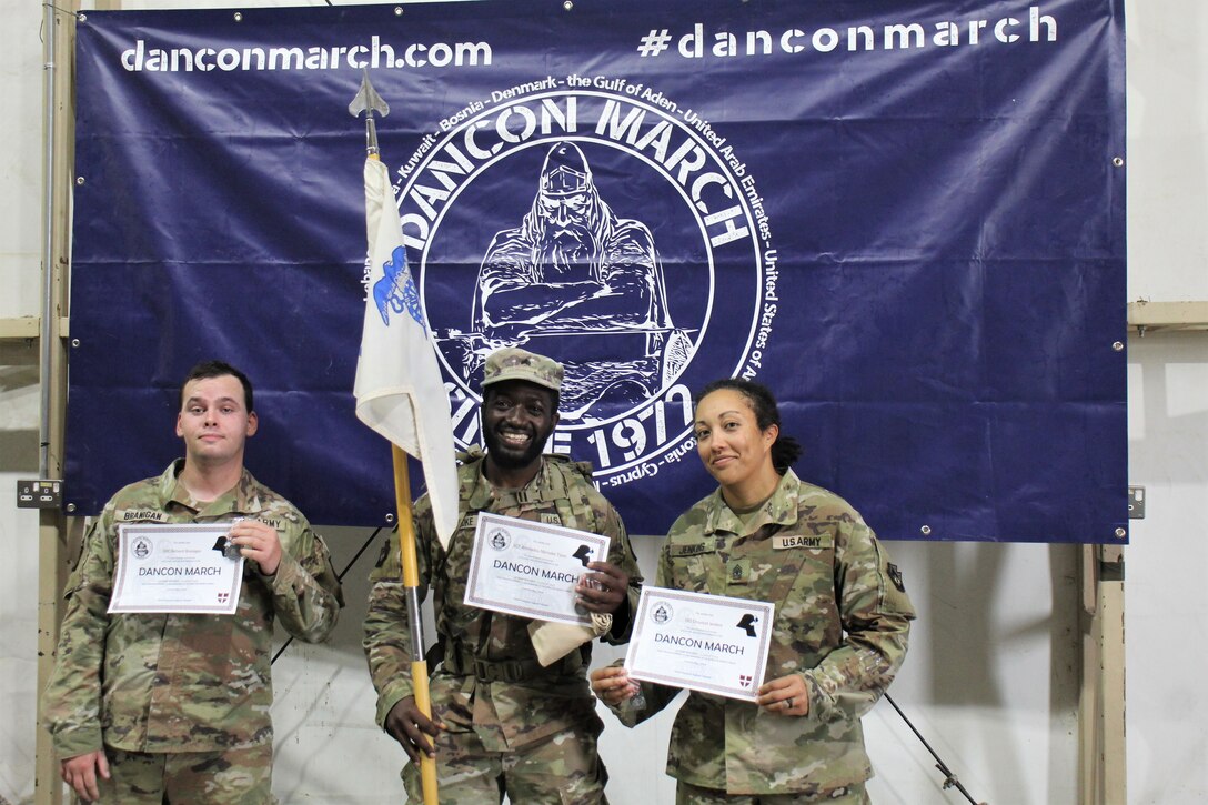 From left, U.S. Army Spc. Richard Branigan, Sgt. Ahmadou Njimoke Tijani and 1st Sgt. Chrystall Jenkins, currently deployed to the Middle East with the 252nd Composite Supply Company, 728th Combat Sustainment Support Battalion, 213th Regional Support Group, receive certificates for completing the Danish Contingent March at Camp Buehring, Jan. 15, 2023. (U.S. Army photo by Spc. Ramon Harris)