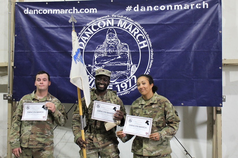 From left, U.S. Army Spc. Richard Branigan, Sgt. Ahmadou Njimoke Tijani and 1st Sgt. Chrystall Jenkins, currently deployed to the Middle East with the 252nd Composite Supply Company, 728th Combat Sustainment Support Battalion, 213th Regional Support Group, receive certificates for completing the Danish Contingent March at Camp Buehring, Jan. 15, 2023. (U.S. Army photo by Spc. Ramon Harris)