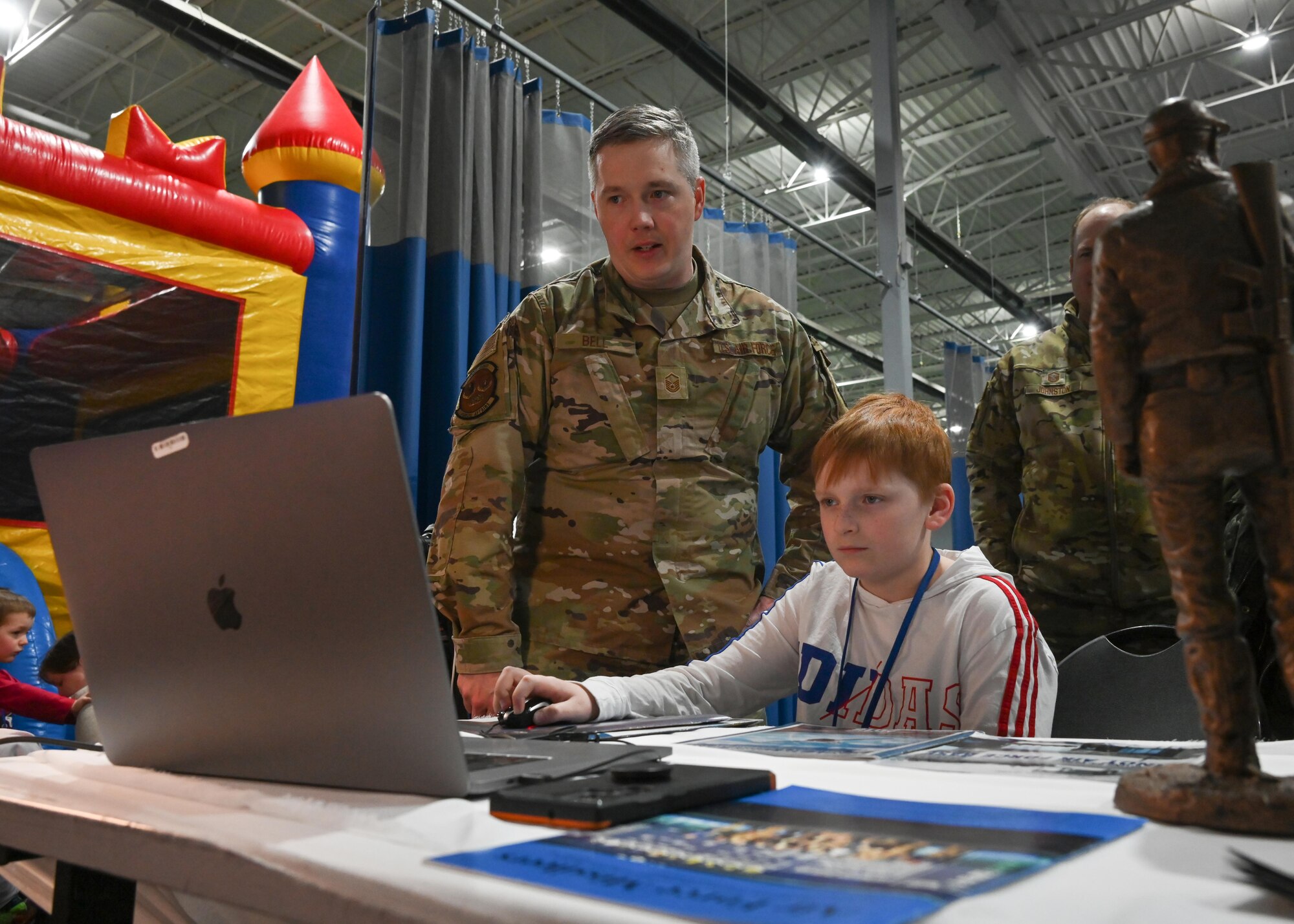 U.S. Air Force Master Sgt. Ryan Bell, 791st Missile Security Forces Squadron 5th Bomb Wing Public Affairs augmentee, teaches kids how to capture imagery and edit footage during Operation Hero at the Community Complex Center at Minot Air Force Base, North Dakota, Jan. 20, 2023. Airmen assigned to 20 different agencies from the 5th Bomb Wing and the 91st Missile Wing showcased their duties, conducted demonstrations, and provided interactive experiences to over 150 families. (U.S. Air Force photo by Senior Airman Caleb S. Kimmell)