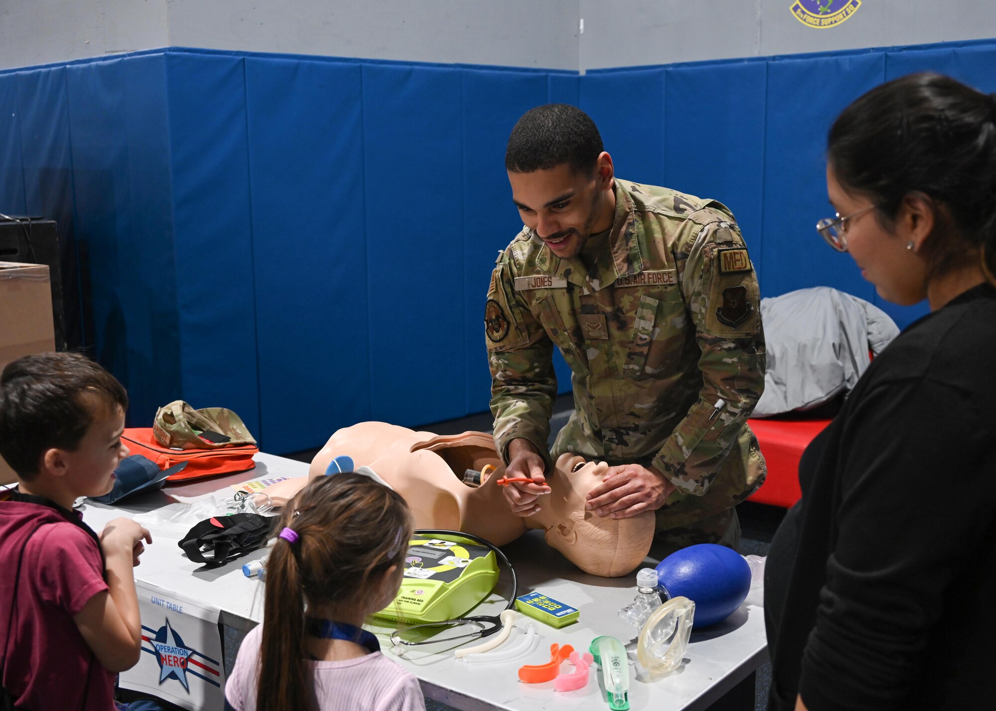 U.S. Air Force Airman First Class Easton Jones, 5th Healthcare Operations Squadron 
ambulance service medical technician, teaches kids emergency breathing techniques as part of Operation Hero at the Community Complex Center at Minot Air Force Base, North Dakota, Jan. 20, 2023. Airmen assigned to 20 different agencies from the 5th Bomb Wing and the 91st Missile Wing showcased their duties in an effort to teach families and their children about how many different career paths they can take in their lives. (U.S. Air Force photo by Senior Airman Caleb S. Kimmell)