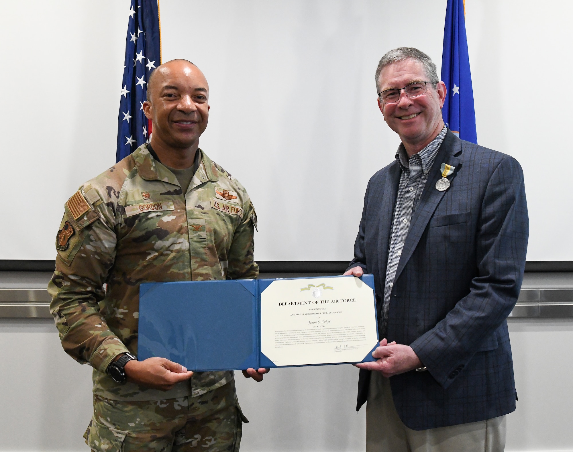 Air Force colonel presenting award citation to civilian