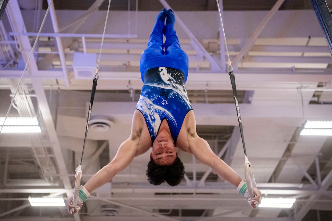 An Air Force cadet does a hand stand on gymnastic rings.