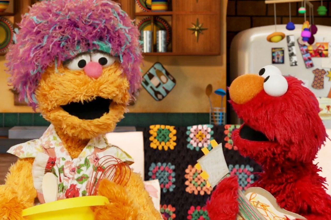 Two Muppets talk; the large one is holding a bowl, and the smaller one holds a cardboard guitar.
