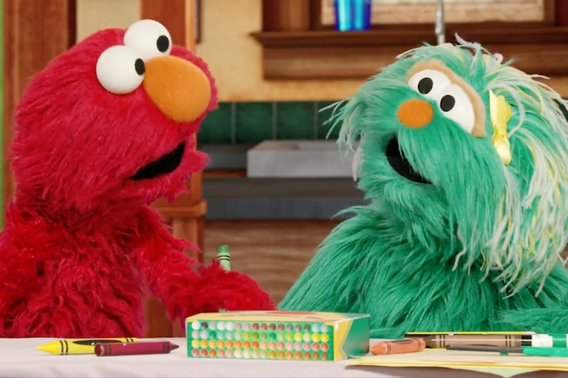 Two Muppets look toward each other while using crayons.