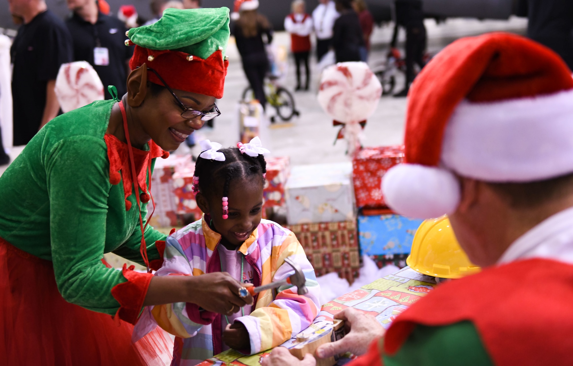 An “elfscort” helps a Salvation Army Angel Tree child in a building activity at the Flight to the North Pole at the 172nd Airlift Wing in Jackson, Mississippi, Dec. 13, 2022. Flight to the North Pole is an annual community outreach event benefiting the Salvation Army Angel Tree program, hosted by the 172nd Airlift Wing, Jackson Mississippi Metro Area Salvation Army and local volunteers. (U.S. Air National Guard photo by Airman 1st Class Shardae McAfee)