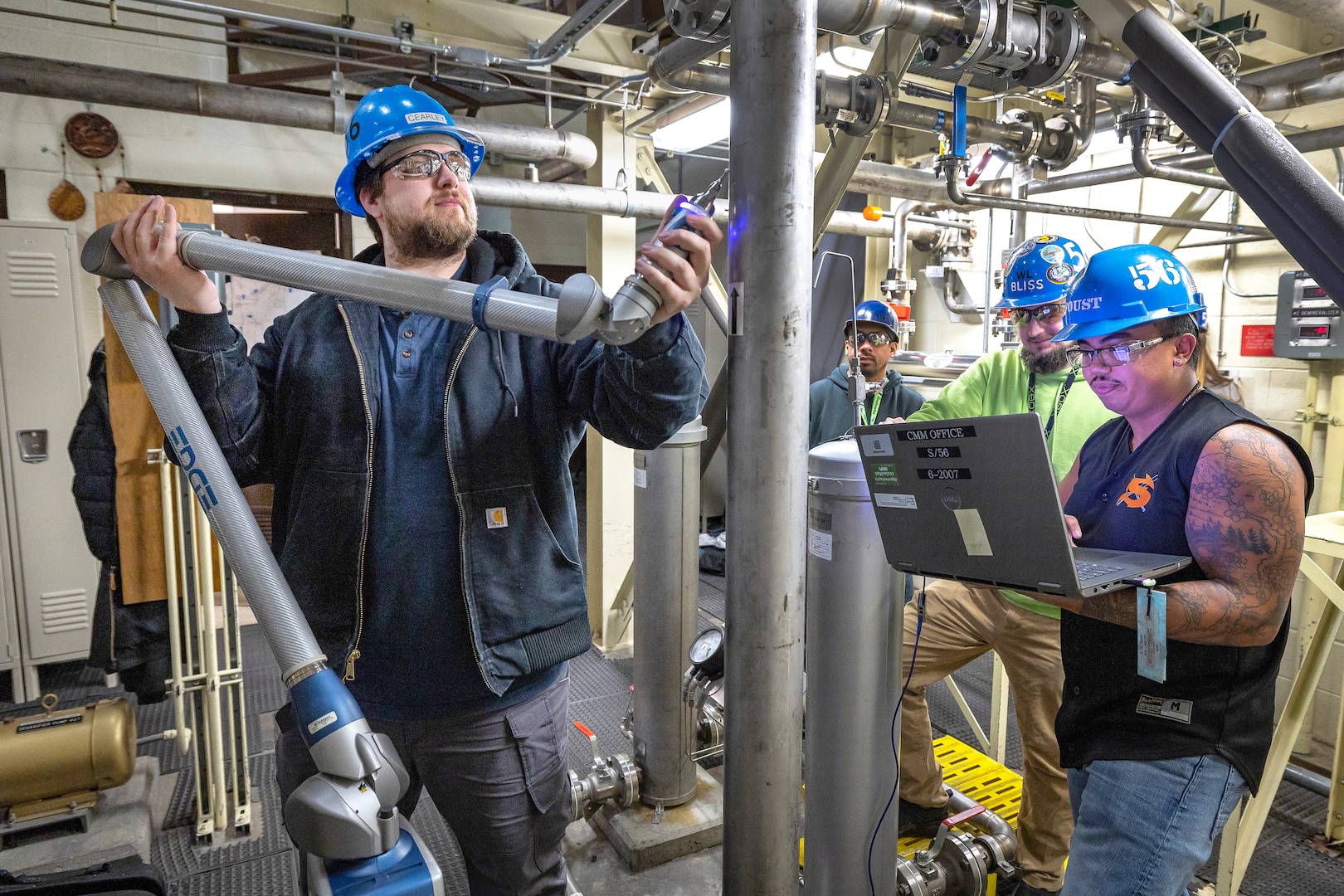Shop 56 pipefitters (from left) Mitchell Clearly, Brandon Bliss and Chris Foust demonstrate the use of the new, portable FARO Arm at the NBK Pure Water Plant December 12, 2022 at Naval Base Kitsap-Bremerton, Washington. (U.S. Navy photo by Scott Hansen)