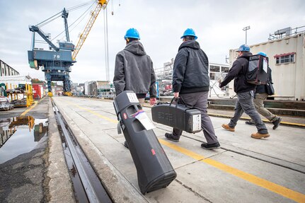 Shop 56 pipefitters (from left) Joseph Hardin, Mitchell Clearly, Trevor Buechner and Dalles Hight deliver new, portable FARO Arm equipment to a job site Dec. 8, 2022, at Puget Sound Naval Shipyard & Intermediate Maintenance Facility in Bremerton, Washington. (U.S. Navy photo by Scott Hansen)