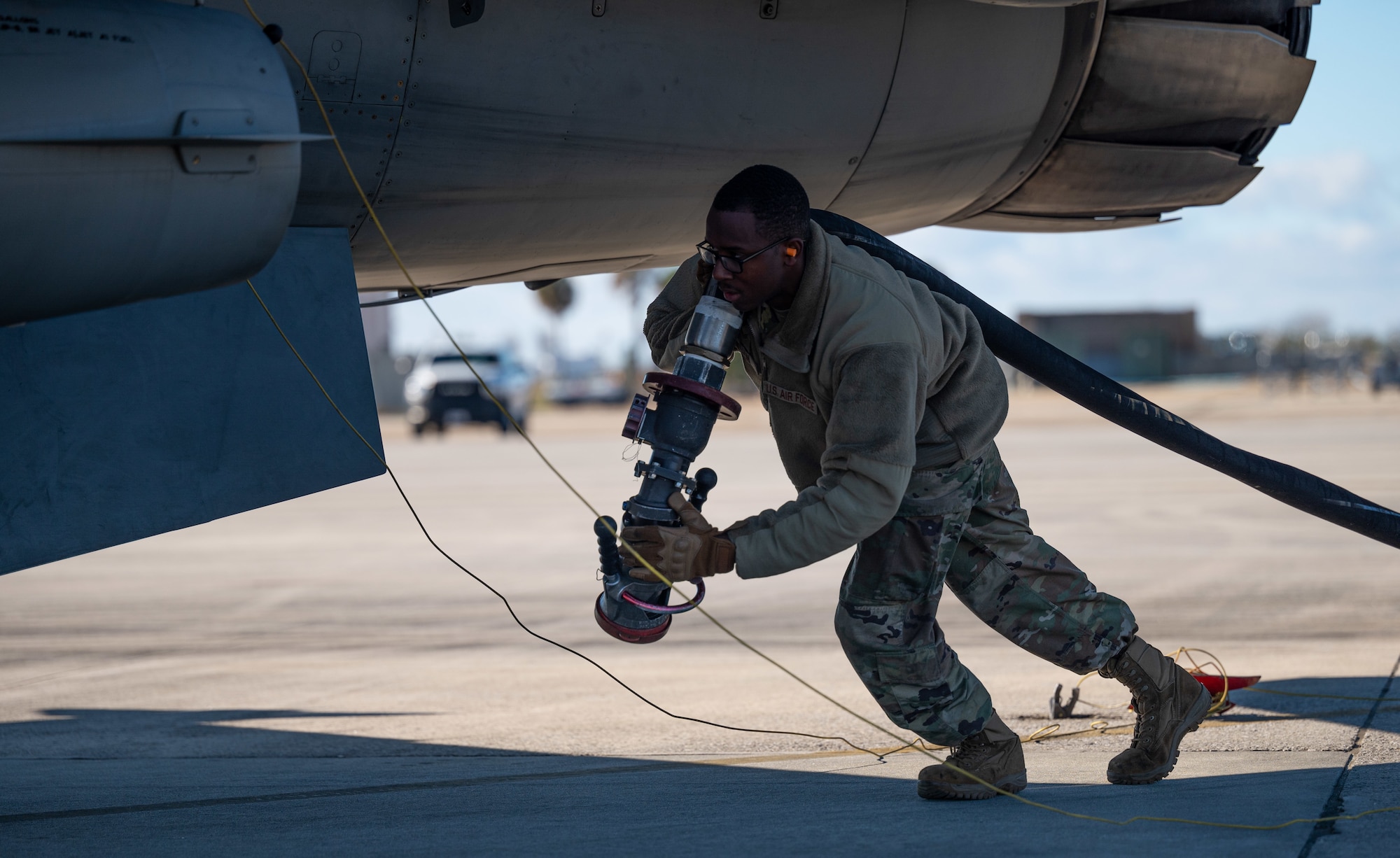 An Airman pulls a fuel hose to an aircraft.