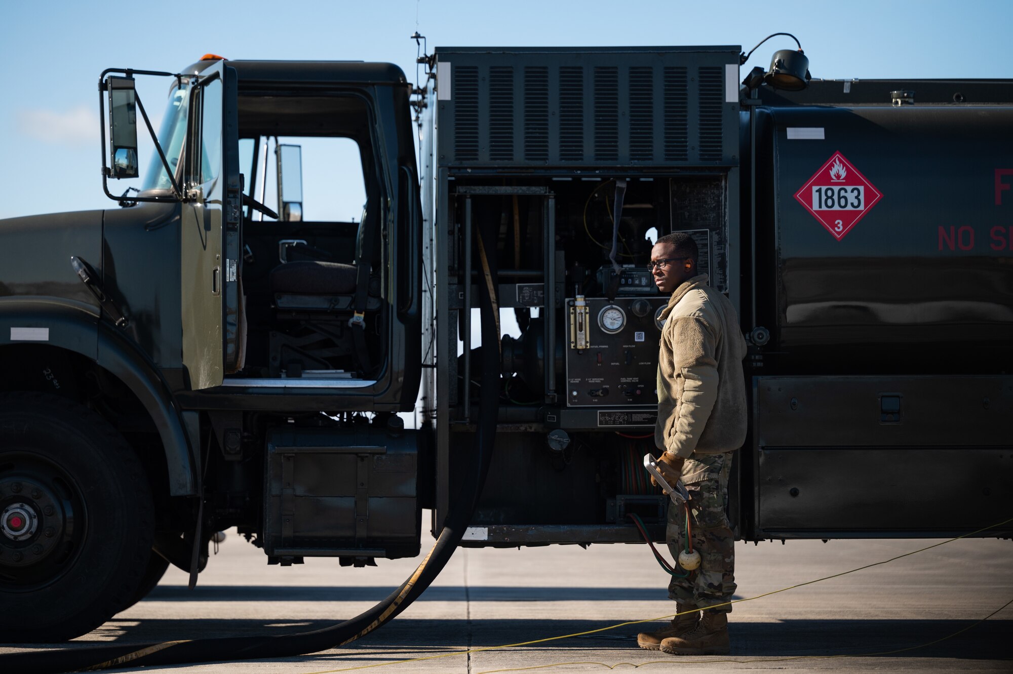 An Airman holds a tablet and stands next to a fuel truck