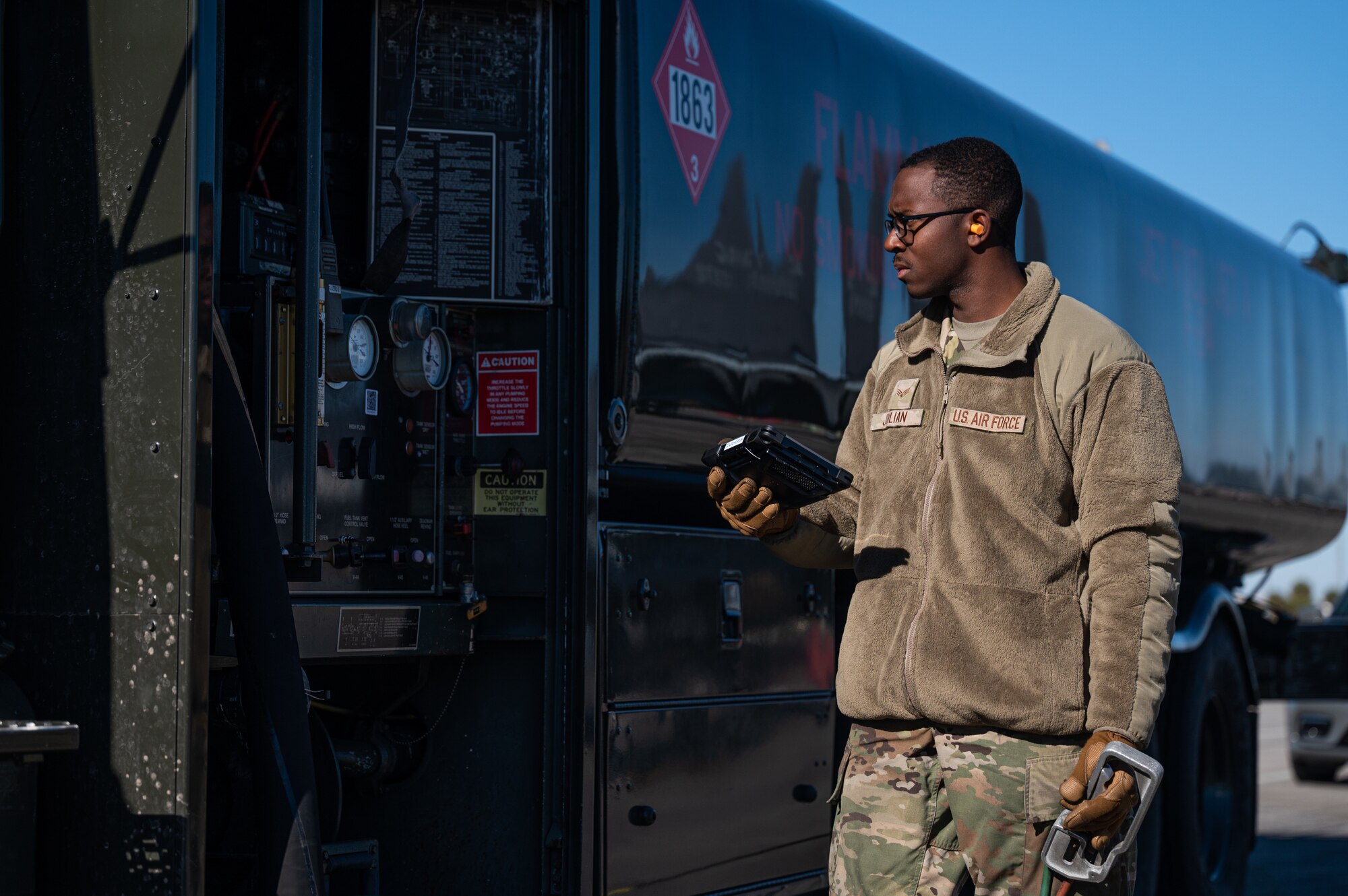 An Airman holds a tablet and stands next to a fuel truck