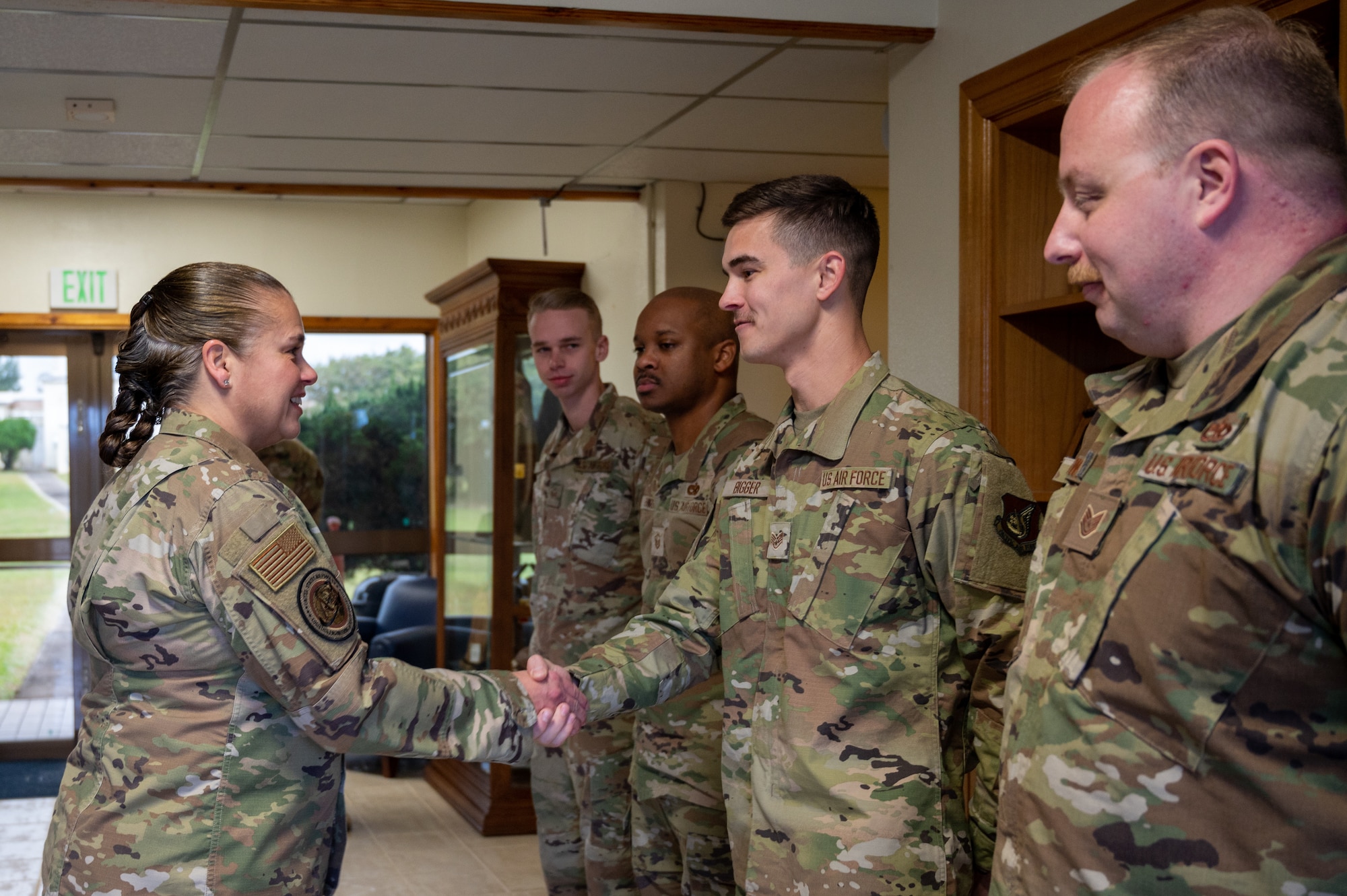 Airmen shaking each other's hand after receiving recognition.