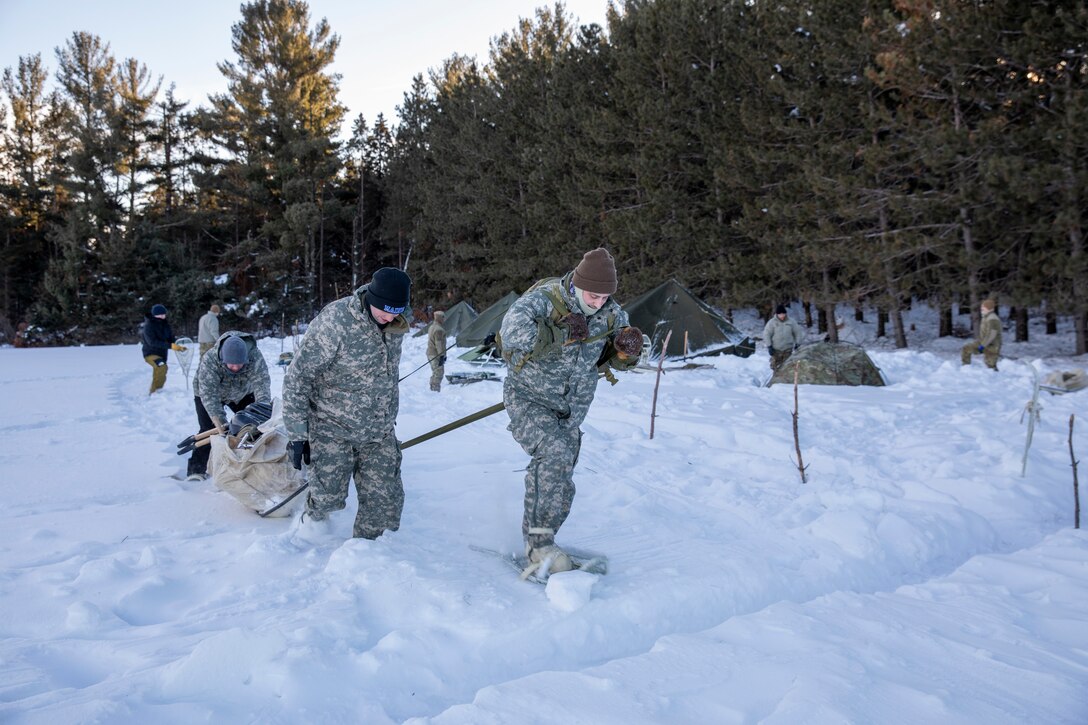 From the right, Maine Air National Guard Tech. Sgt. Hudson Stanley, Staff Sgt. Matthew Varney, and Tech Sgt. Emily Marecaux, with the 265th Combat Communications Squadron, to stay warm in freezing temperatures while performing different aspects of their jobs during a cold-weather focused, annual training event at Camp Ripley, Minnesota, Jan. 26, 2023.