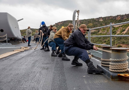(Jan. 30, 2023) Sailors assigned to the Ticonderoga-class guided-missile cruiser USS Leyte Gulf (CG 55) heave line from the pier as the ship arrives in Souda Bay, Greece, for a scheduled port visit, Jan. 30, 2023. The George H.W. Bush Carrier Strike Group is on a scheduled deployment in the U.S. Naval Forces Europe area of operations, employed by U.S. Sixth Fleet to defend U.S., allied, and partner interests.