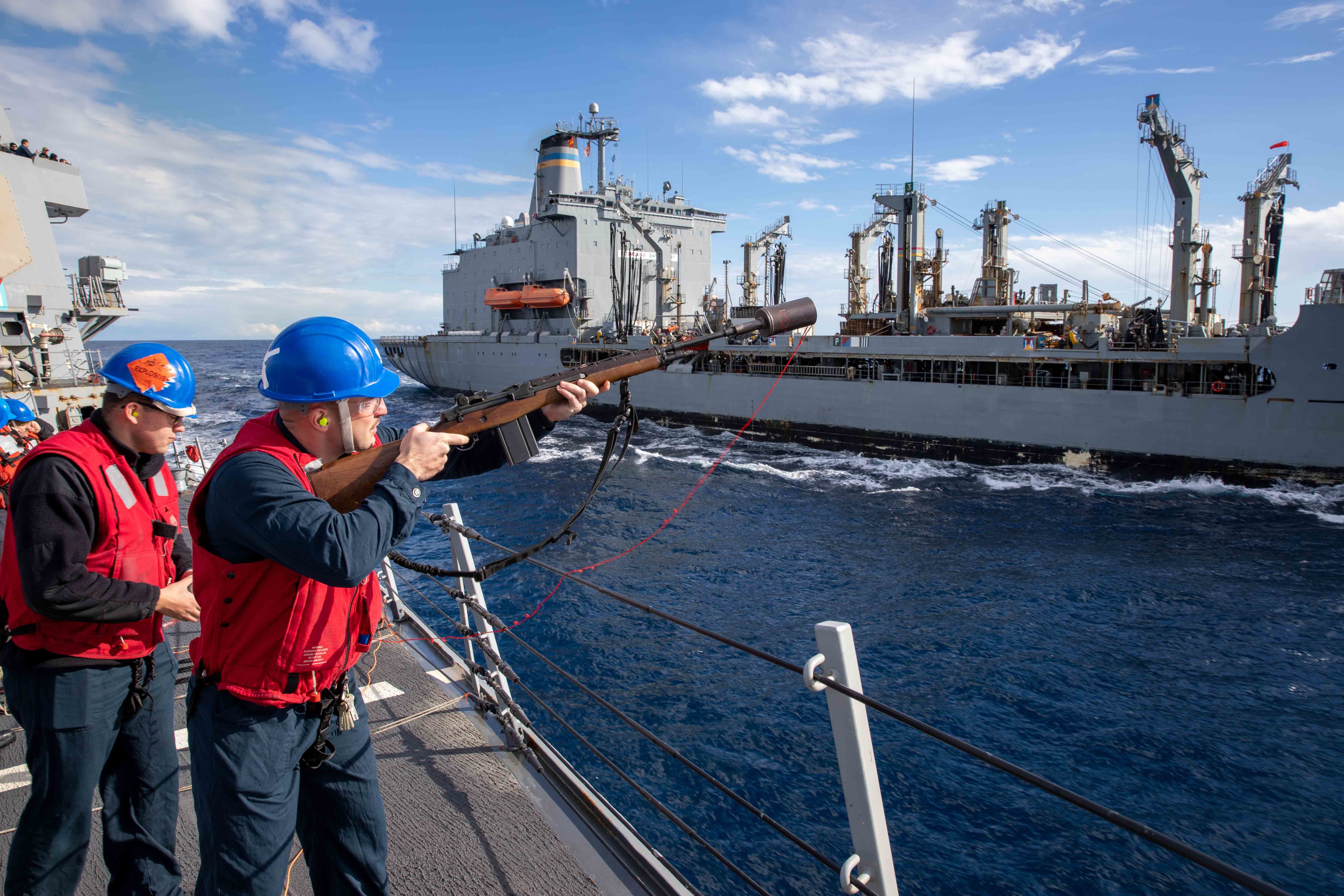 Gunner’s Mate 3rd Class Conner McKinley, assigned to the Arleigh Burke-class guided-missile destroyer USS Nitze (DDG 94), fires a shot line to the Military Sealift Command Henry J. Kaiser-class fleet replenishment oiler USNS Kanawha (T-AO 196) during a replenishment-at-sea, Jan. 28, 2023.