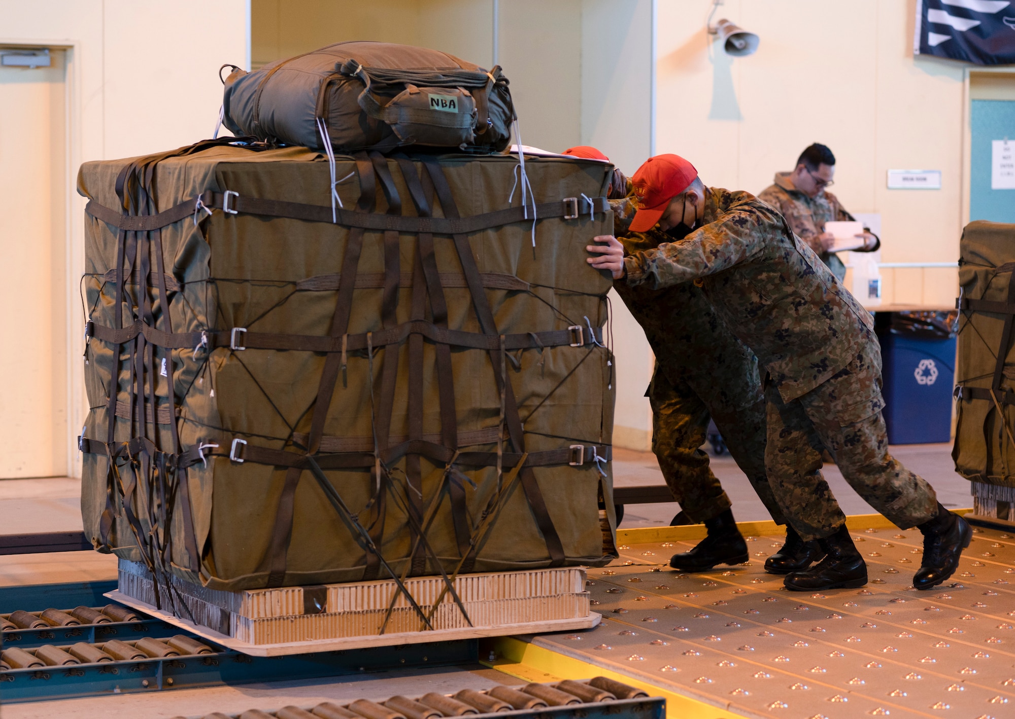 Two Japan Ground Self-Defense Force soldiers push a Containerized Delivery System bundle