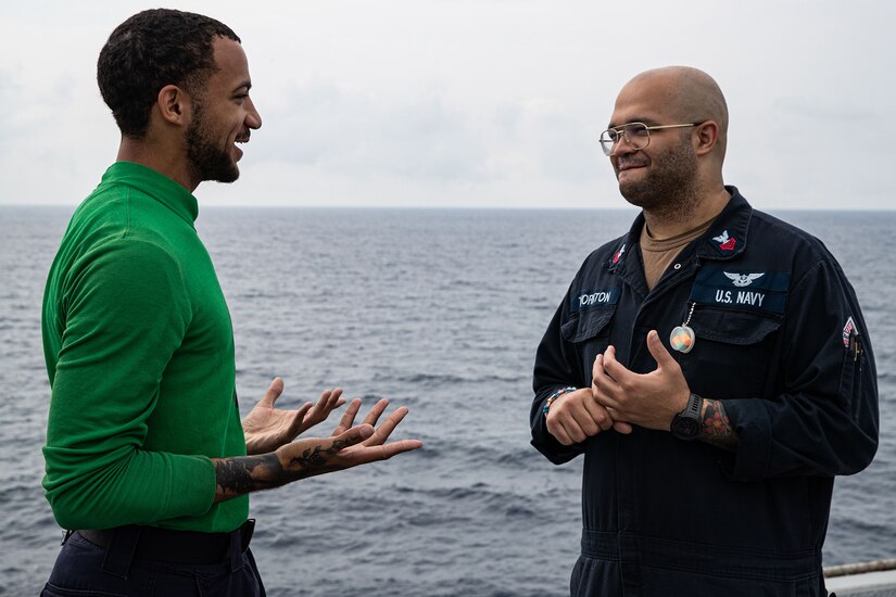 Two sailors stand on a ship's flight deck.