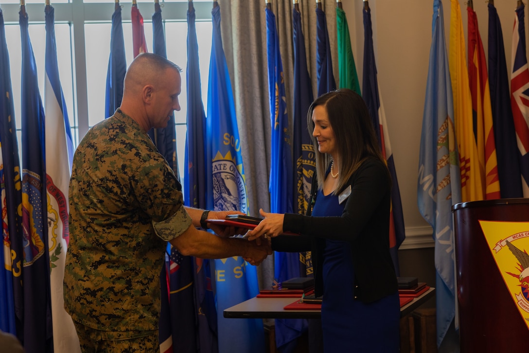 U.S. Marine Corps Air Station (MCAS) Cherry Point Commanding Officer Col. Brendan Burks passes a medal and certificate to Hailey Stephenson, housing management specialist, during the Civilian of the Year award ceremony at Miller’s Landing, MCAS Cherry Point, North Carolina, June 5, 2023. The ceremony spotlighted six total awardees from various departments on the installation who exceeded performance expectations to serve the MCAS Cherry Point community and beyond. (U.S. Marine Corps photo by Cpl. Jade Farrington)