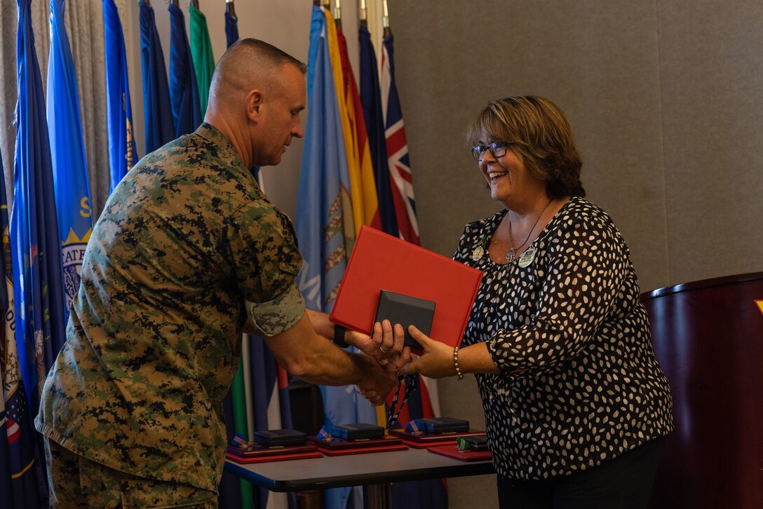 U.S. Marine Corps Air Station (MCAS) Cherry Point Commanding Officer Col. Brendan Burks passes a medal and certificate to Beverly Guerin, administrative specialist, during the Civilian of the Year award ceremony at Miller’s Landing, MCAS Cherry Point, North Carolina, June 5, 2023. The ceremony spotlighted six total awardees from various departments on the installation who exceeded performance expectations to serve the MCAS Cherry Point community and beyond. (U.S. Marine Corps photo by Cpl. Jade Farrington)