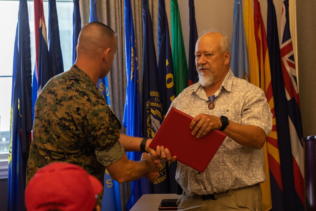 U.S. Marine Corps Col. Brendan Burks, U.S. Marine Corps Air Station Cherry (MCAS) Point commanding officer congratulates Kenneth Cobb, range management officer, during the Civilian of the Year award ceremony at Miller’s Landing, MCAS Cherry Point, North Carolina, June 5, 2023. The ceremony spotlighted six total awardees from various departments on the installation who exceeded performance expectations to serve the MCAS Cherry Point community and beyond. (U.S. Marine Corps photo by Cpl. Jade Farrington)