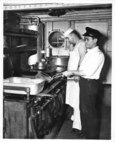 USCG Cooks, including a Filipino Steward, cook aboard an unnamed cutter's galley.