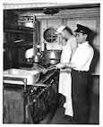 USCG Cooks, including a Filipino Steward, cook aboard an unnamed cutter's galley.