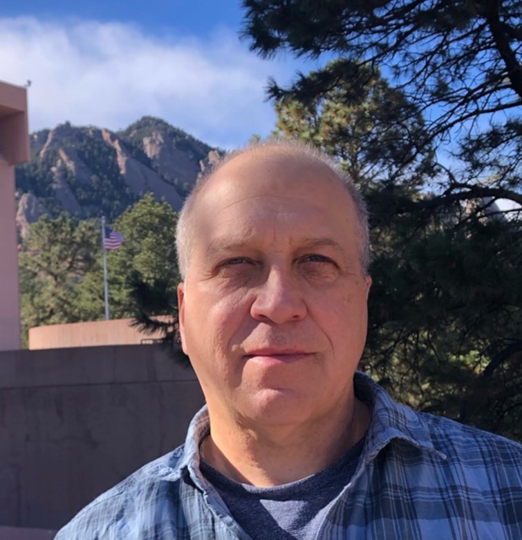Photo of Caucasian man standing with mountains in the background.