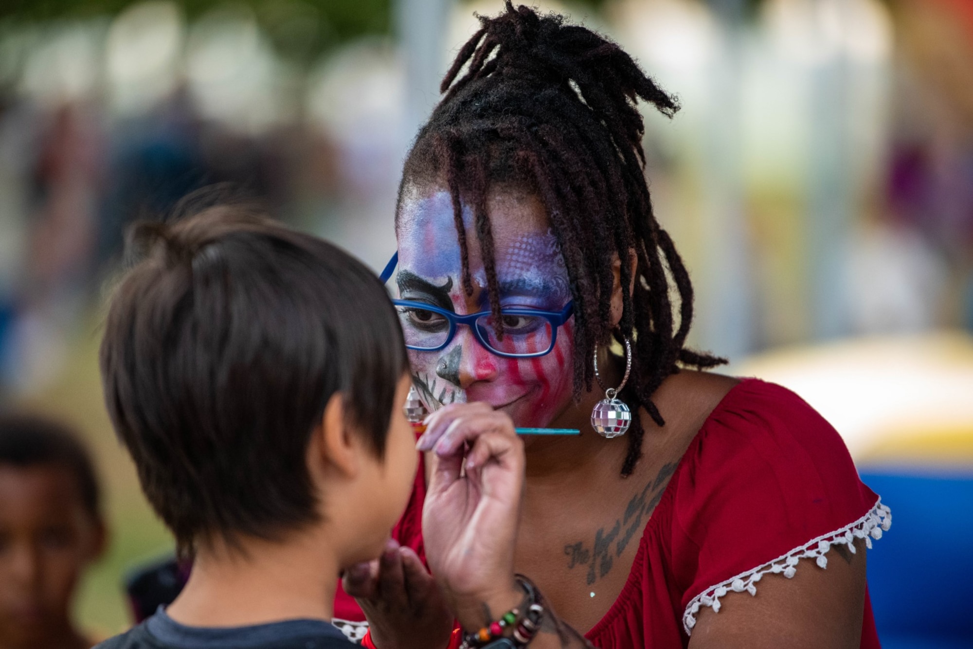Military spouse Serra Bowman applies face paint to Super Saber Day attendants at Spangdahlem Air Base, Germany, July 2, 2023.