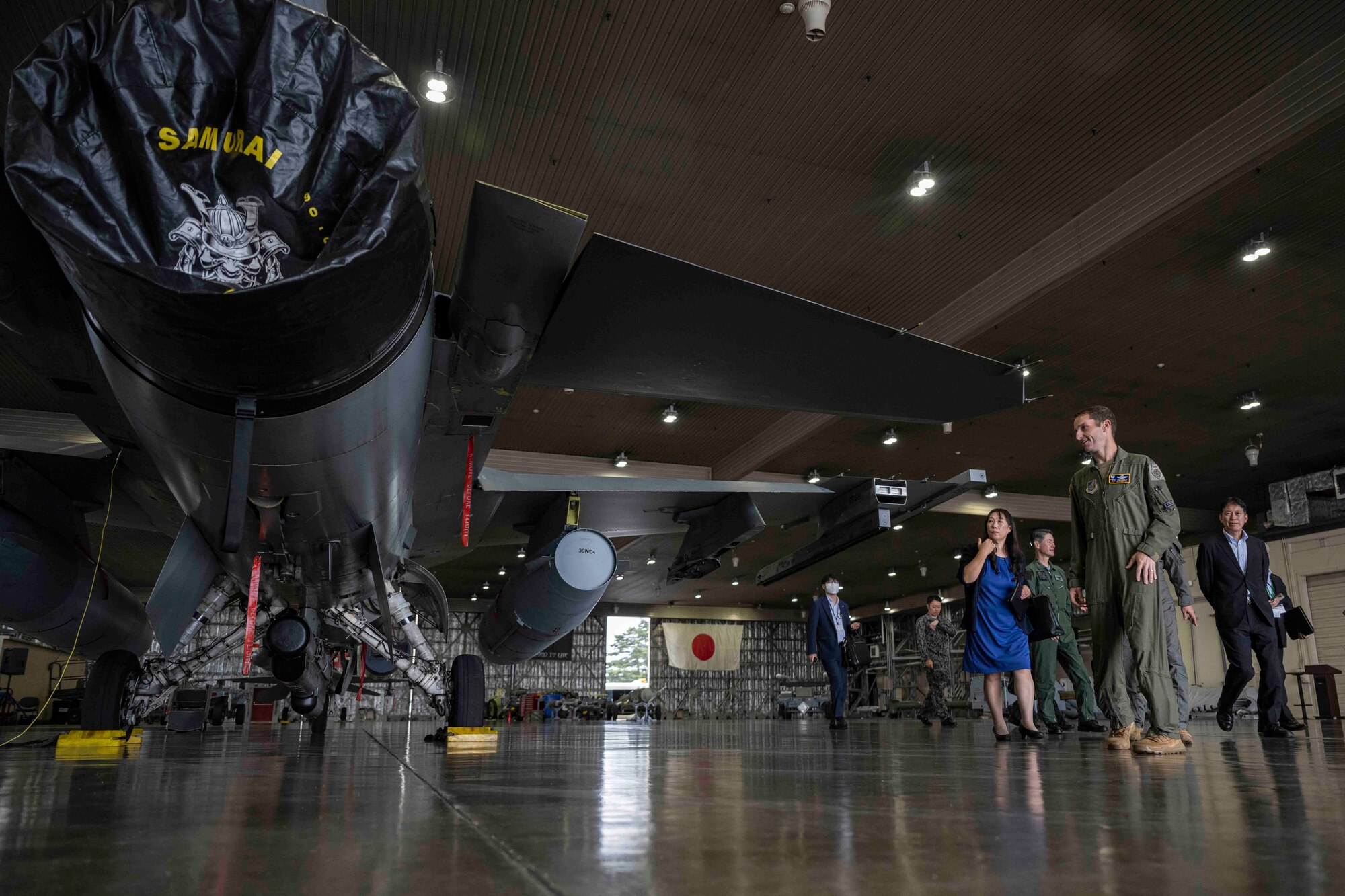 A group of people walk around a fighter jet in a hangar at Misawa Air Base.
