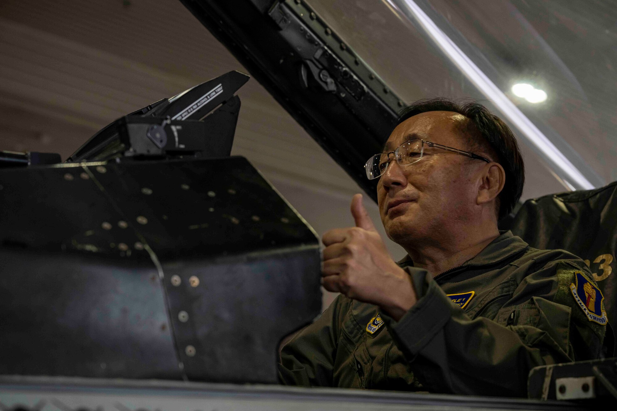 A man gives a thumbs up as he sits inside the cockpit of a fighter jet in a hangar at Misawa Air Base.
