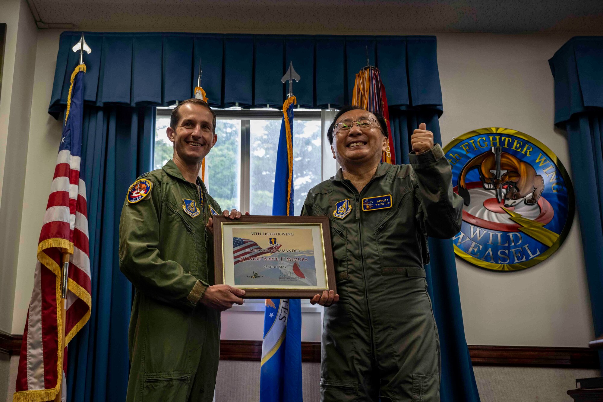 Two people pose for a photo with a certificate in a photo frame.