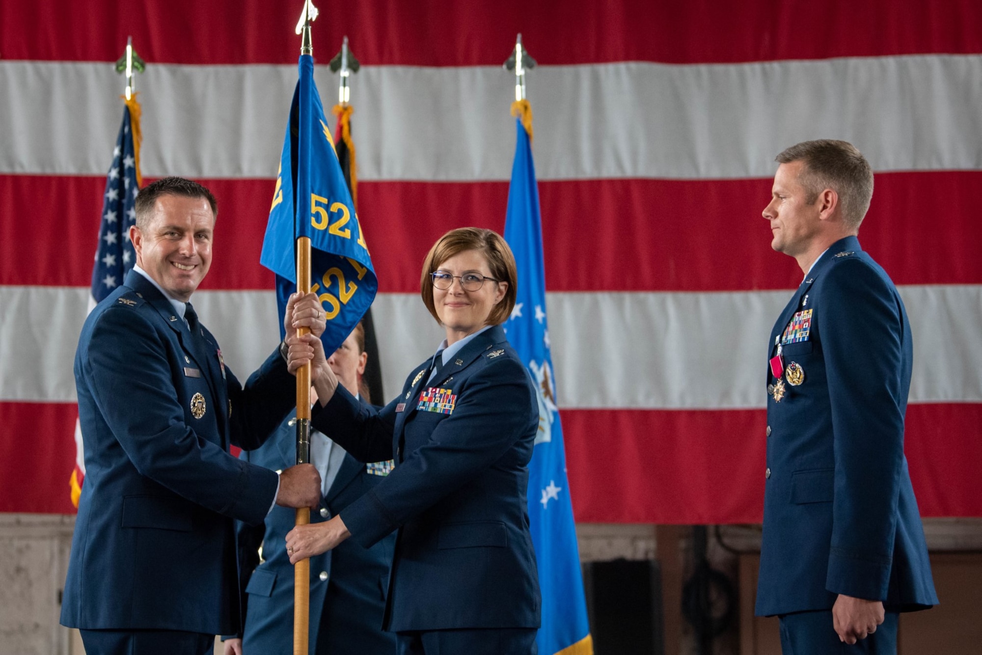U.S. Air Force Col. Kevin Crofton, 52nd Fighter Wing commander, (left), passes the guidon to Col. Karri Roman, 52nd Medical Group incoming commander (center) June 30, 2023, on Spangdahlem Air Base, Germany.