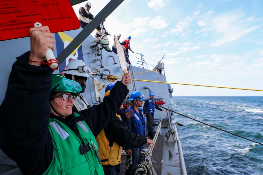 A sailor holds paddles to signal another ship.