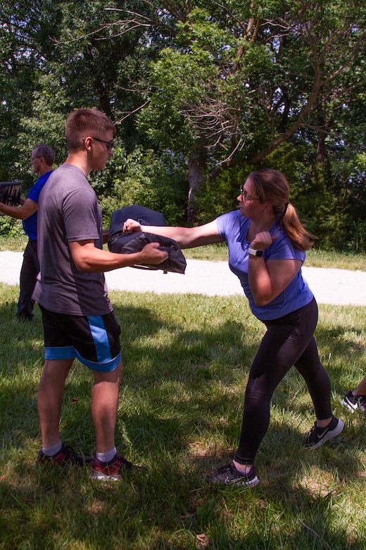 Two trainee rangers engage in self defense training with trees in the background.