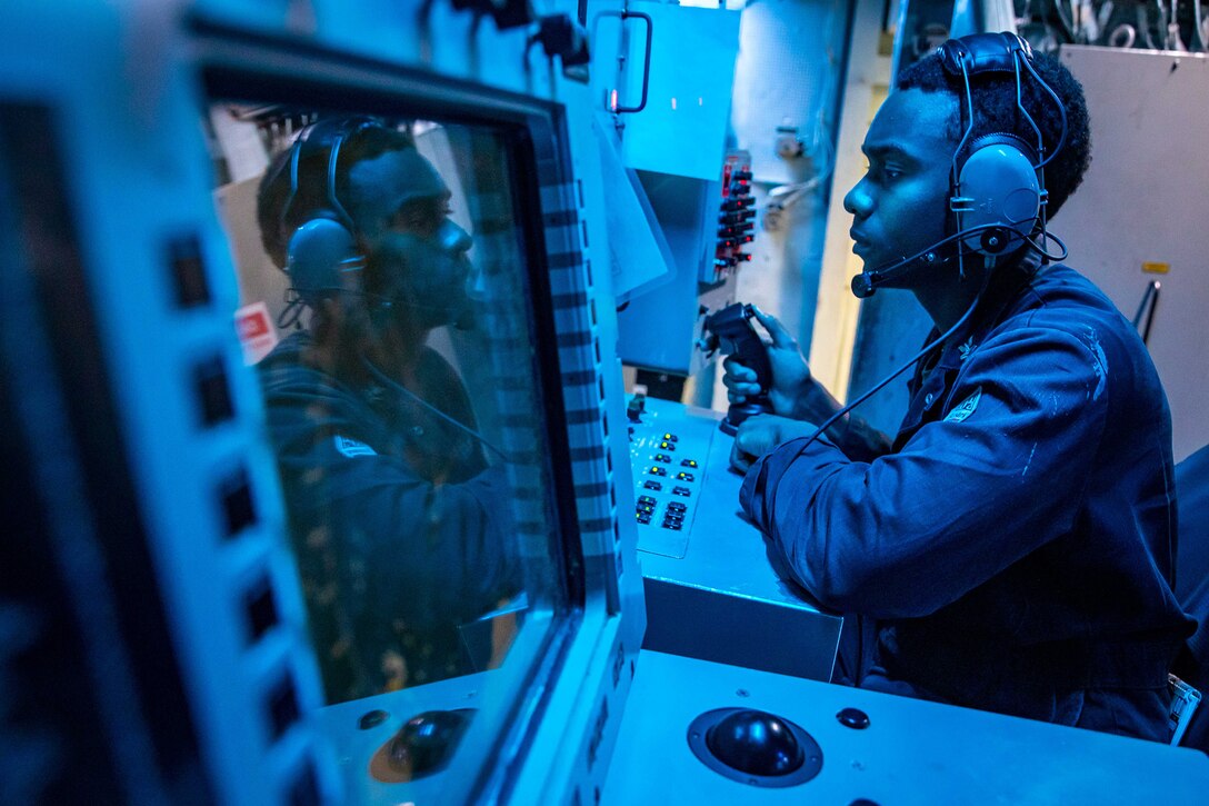 A sailor operates a joystick device on a computer during an inbound sea and anchor evolution.