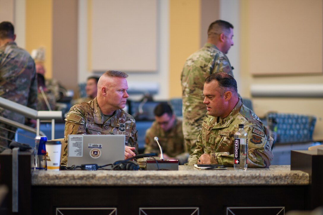 Two men in military uniforms talk to each other.