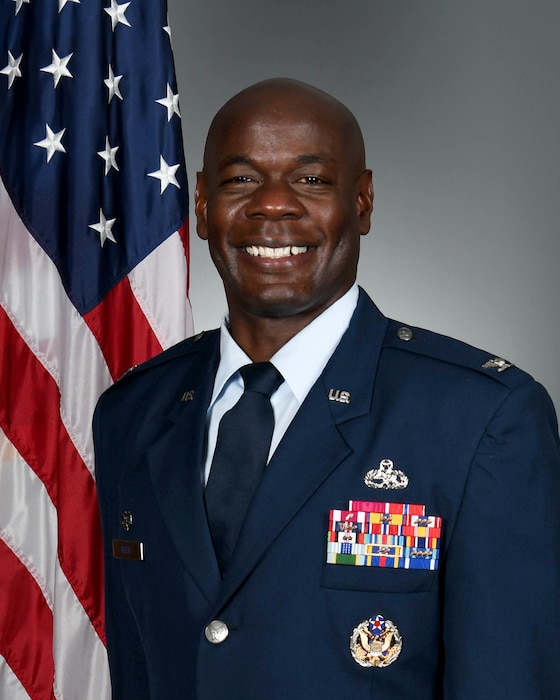 Headshot photo of man with American flag in the background