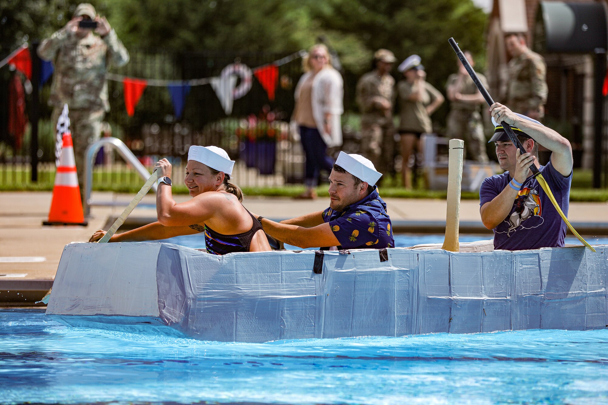 (Left to right) Senior Airman Stephanie Gillespie, 445th Maintenance Squadron fabrication flight non-destructive inspection technician, Staff Sgt. Lawrence Depasquale and Master Sgt. Bradley Swindall, both 445th MXS aircraft structural maintenance mechanics, paddle to the finish line during the Wright-Patterson Air Force Base Cardboard Boat Regatta held on base at Patterson Pool June 30, 2023. The 445th MXS team made their boat, Ship for Brains, out of cardboard, glue and tape. They won “The Packed Pontoon Award” for most people on a boat. Additionally, they won the “Soggy Bottom Award” for having the last boat standing during the battle royal in which the participants attempt to sink each other’s boats by ramming or filling with water by use of water guns or buckets. Ten teams participated in the event this year with more than 100 people in attendance.