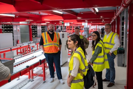 Members of U.S. Army Medical Logistics Command’s Integrated Logistics Support Center tour the U.S. Army Medical Materiel Center-Europe in late May. Pictured, from left in yellow vests, are data scientists Julia Contarino and Tajesvi Bhat, and Arthur Braithwaite, director of the ILSC’s Logistics and Technical Support Directorate. The LTSD data analysis team visited USAMMC-E to learn more about operations, provide training and support the setup of an analytics dashboard to help streamline operations. (U.S. Army photo by Joel Cook)