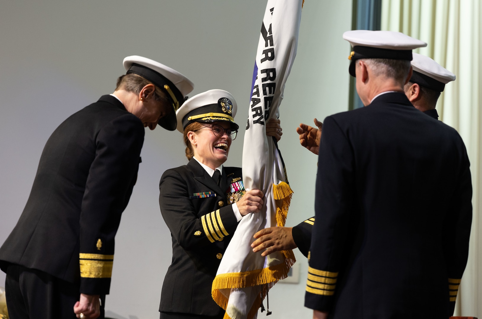 U.S. Navy Capt. Melissa Austin who assumed directorship of Walter Reed during a change of directorship ceremony in Memorial Auditorium, passes the hospital flag as part of the ceremony held on July 5, 2023.